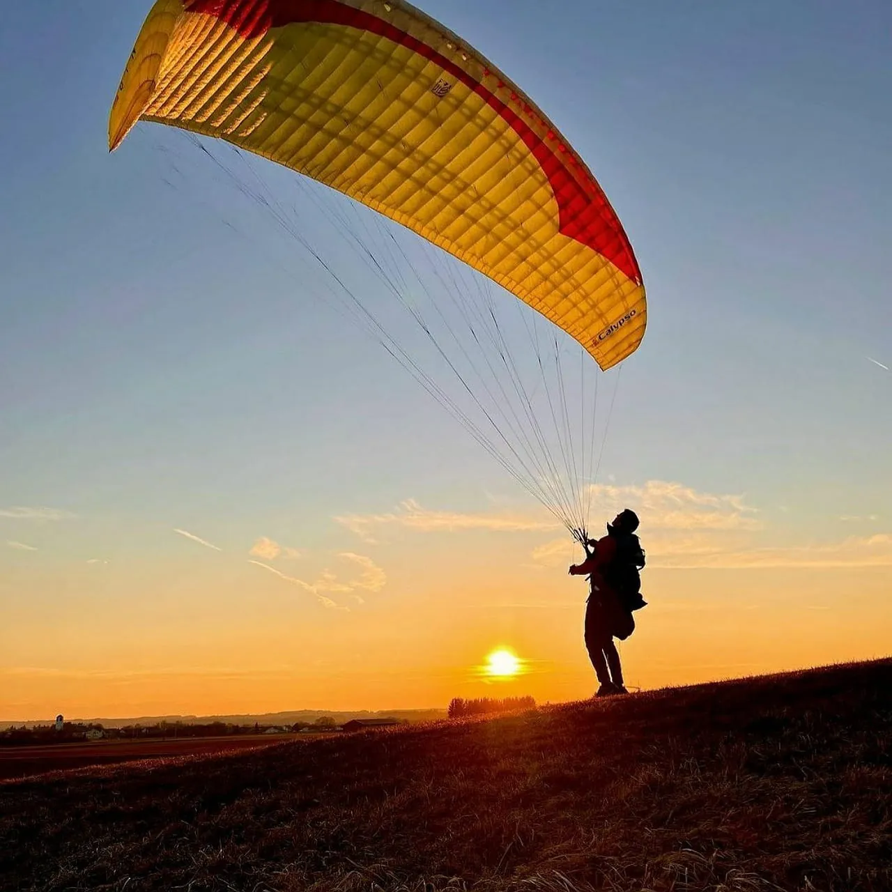 Paraglider silhouetted at sunset