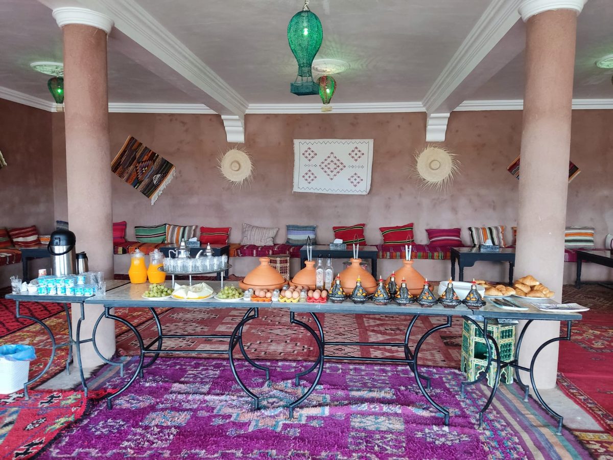 A long breakfast table laid out inside a traditional tent with rugs and lanterns