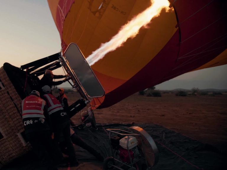 A balloon envelope lying on its side being filled with hot air from the burner