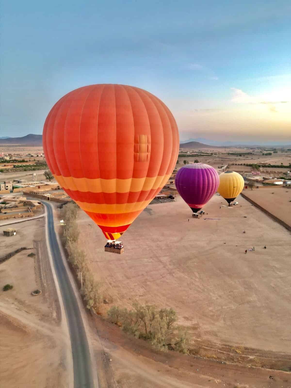Hot air balloons rising over the dry plain outside Marrakech at first light